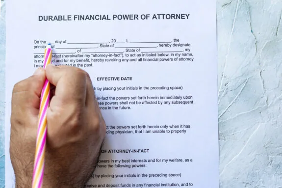 Person filling Durable financial power of attorney form on bright background